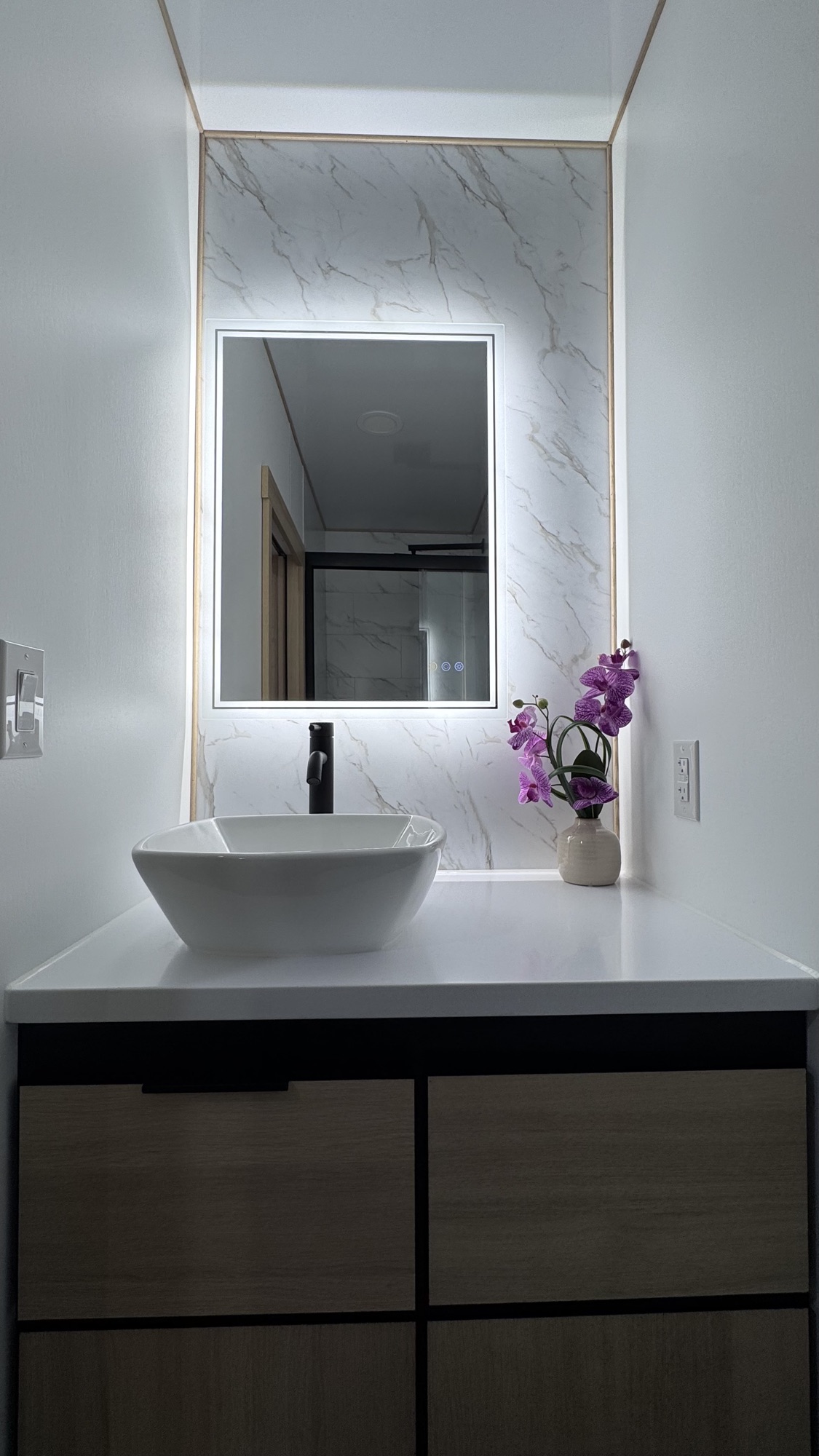 Model A bathroom vanity with white vessel sink, backlit LED mirror, and marble backsplash