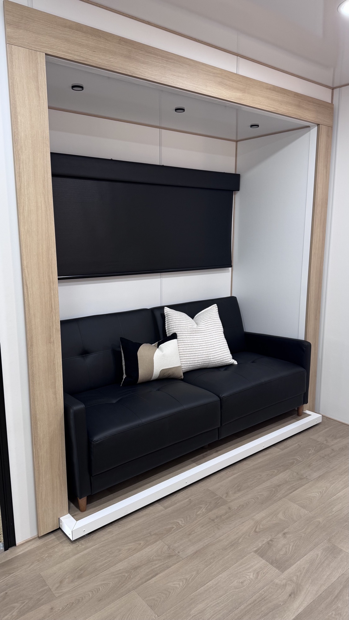Black leather convertible sofa with blackout window shade and decorative pillows in the Model A lounge