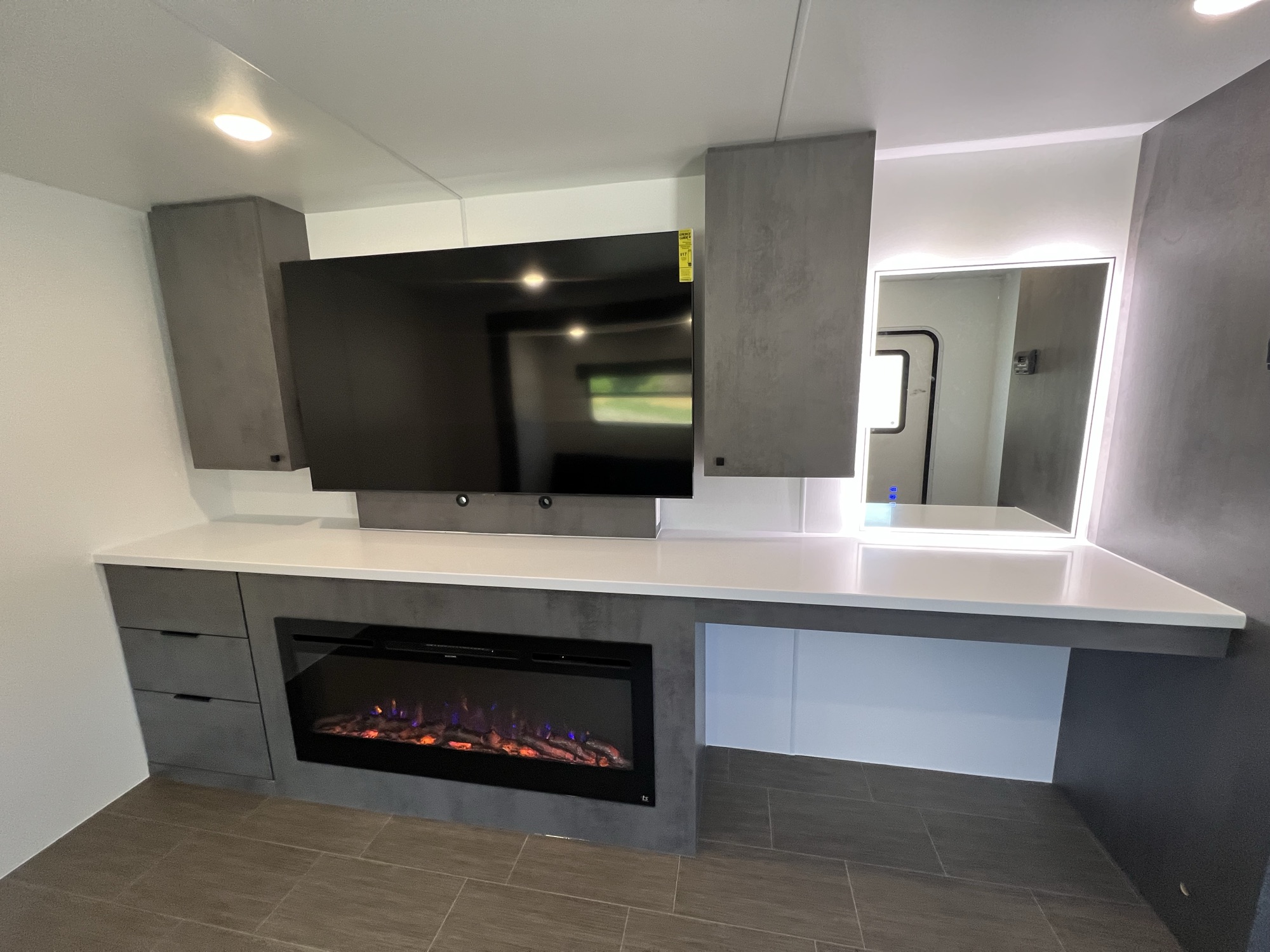 Lit electric fireplace, backlit vanity mirror, beverage fridge, and microwave column