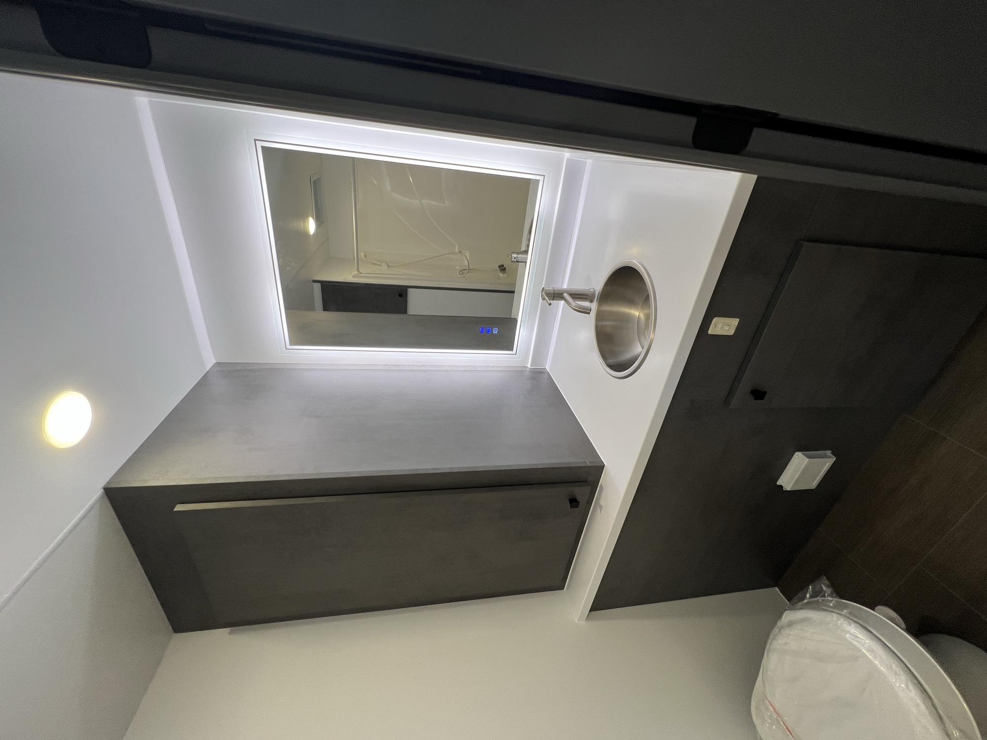 Lit vanity mirror with quartz counter, microwave, and beverage fridge column