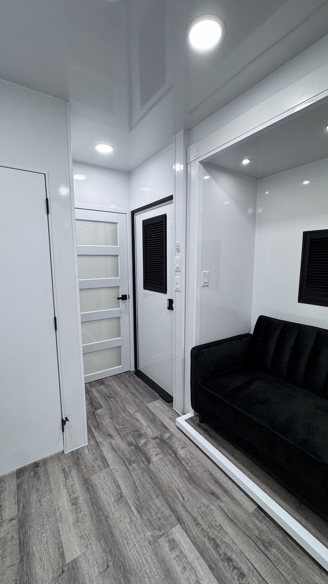 Entry area showing the interior door, paneled storage, and the adjoining lounge with black sofa