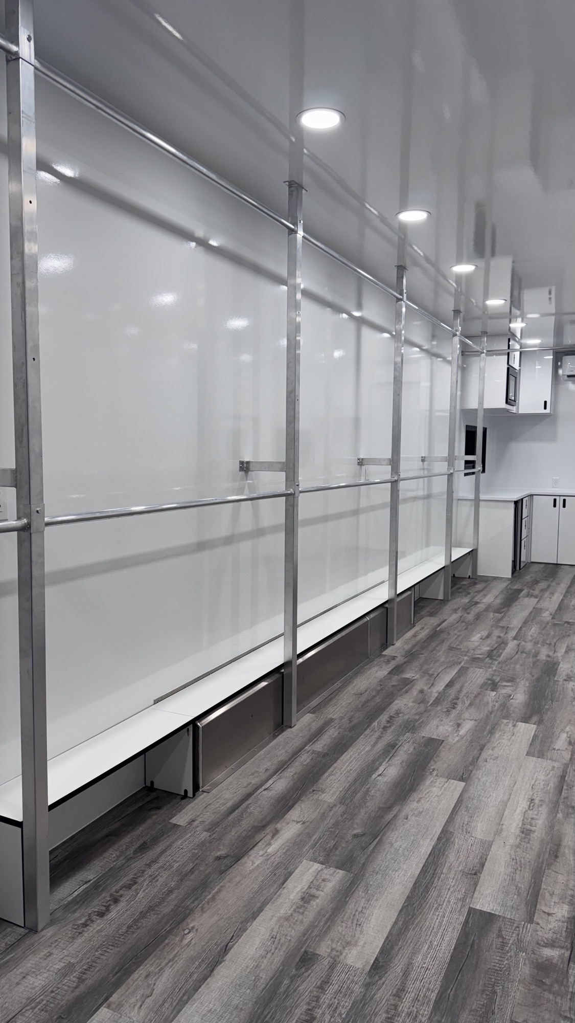 Side wall of the wardrobe trailer with double-tier hanging bars, lower bench storage, and aluminum framing
